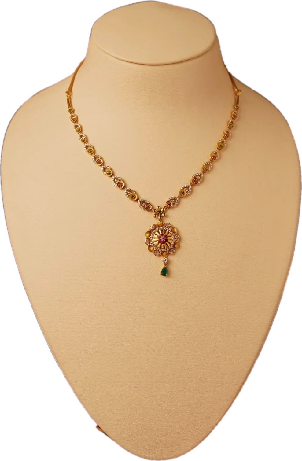 Gold necklace with diamond and emerald links and a floral pendant with an emerald drop on a cream display bust