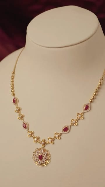 Gold necklace with ruby drops on a display bust