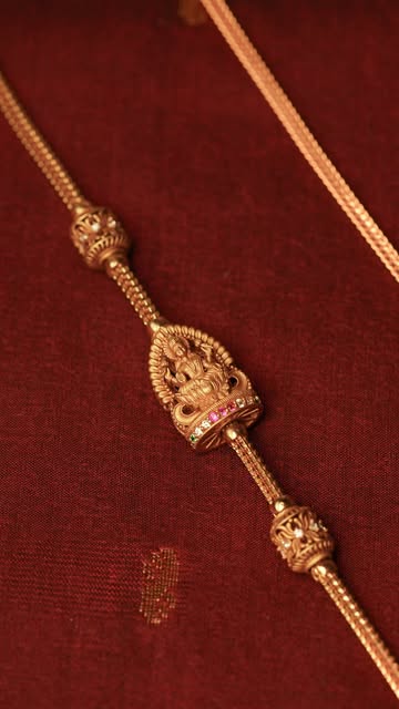 Gold chain with a Lakshmi mugappu on maroon silk